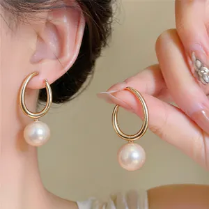 Nahaufnahme eleganter goldener Creolen mit glänzenden Perlenanhängern für jeden Tag