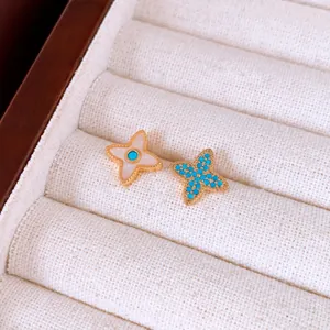 Gros plan détaillé de boucles d'oreilles étoile dorées avec nacre et détails turquoise.