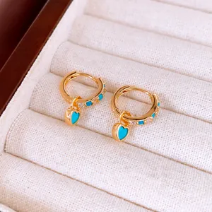 Détail de boucles d'oreilles créoles plaquées or 18 carats avec pendentifs cœurs turquoise