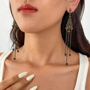 Detailopname van vintage bronzen kwastjesoorbellen met een verfijnd bloemmotief op een model
