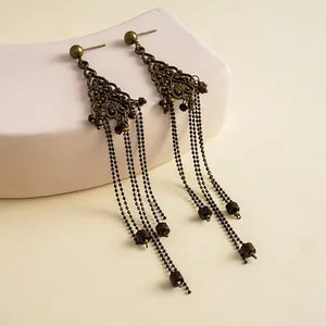 Detailopname van vintage holle bloemoorbellen met lange bronzen metalen kwastjes.