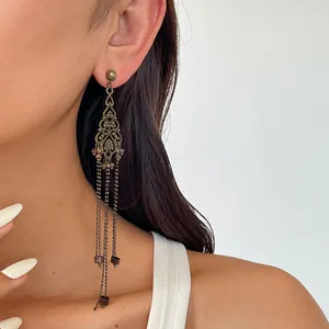 Detailopname van vintage holle metalen bloem kwast oorbellen gedragen door een model