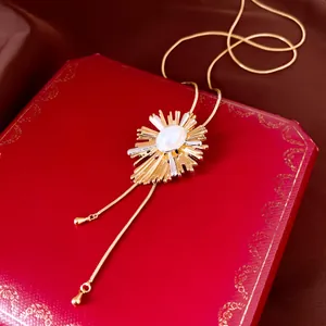 Detailopname van een elegante gouden zonnestraal ketting met parel op een rode geschenkdoos