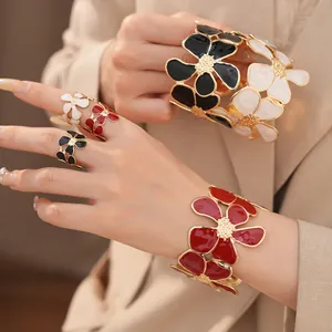 Close-up van een elegante set emaille bloemenringen en armbanden in rood en zwart