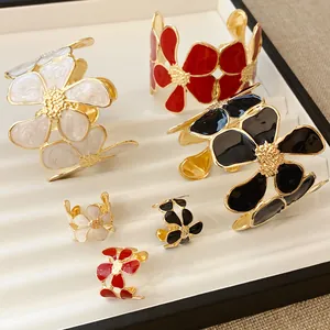 Elegante vergulde emaille bloemensieradenset met open ringen en bijpassende armbanden.