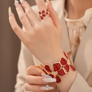 Detailweergave van een model met een rode emaille bloemring en gouden armbandset