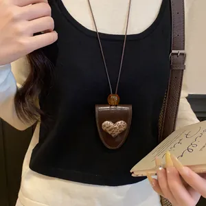 Nahaufnahme der Retro-Leder-Herz-Halskette mit Leopardenmuster auf einem schwarzen Pullover.
