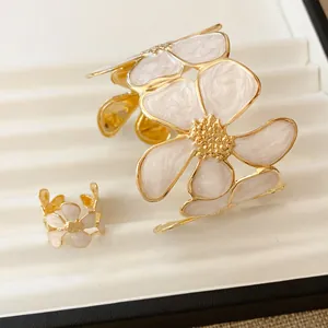 Detail van witte emaille bloemensieradenset met open armband en bijpassende ring