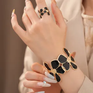 Gedetailleerd overzicht van de elegante zwarte en gouden bloemen ring en armband set