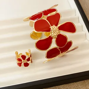 Gedetailleerde opname van luxe rode geëmailleerde bloem open ring en armband set