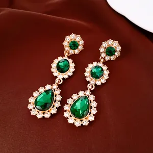 Detailweergave van vintage smaragdgroene oorbellen met glanzende druppels en stras