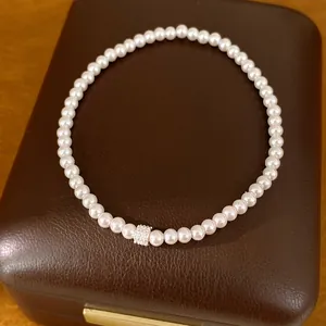 Elegant wit parelarmbandje met een centraal detail van zirkonia steentjes detailopname