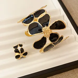 Gedetailleerd overzicht van elegante zwarte emaille bloem armband en ring set in goud