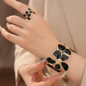 Gedetailleerde weergave van de elegante zwarte geëmailleerde bloemenring en armband