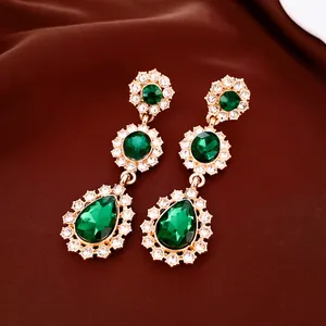 Elegante smaragdgroene hangende oorbellen met kristallen op luxe satijnen achtergrond