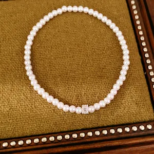 Close-up van elegante parelarmband met een centrale zirkonia kraal op vintage dienblad