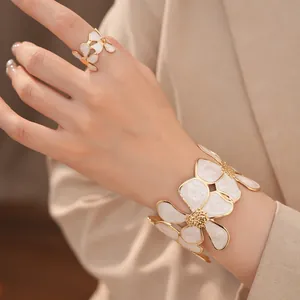 Detailopname van elegante witte emaille bloem open ring en manchet armband set
