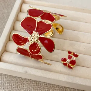 Gedetailleerd overzicht van de rode emaille bloem armband en ring set in goud finish