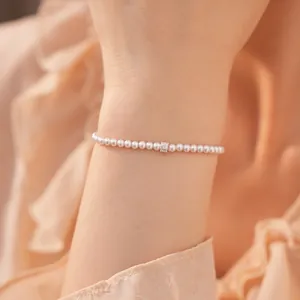 Gedetailleerde close-up van een elegante parelarmband met CZ-accent op de pols