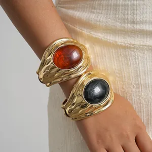 Primo piano di grossi bracciali vintage dorati con resina ovale ambra e marmo intarsiata