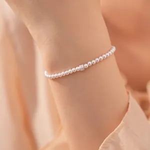 Dichtbij van een elegante parelarmband met een fonkelende zirkoonkraal om de pols