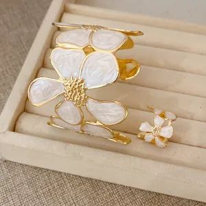Detailweergave van de witte emaille bloem manchetarmband en bijpassende verstelbare ring.