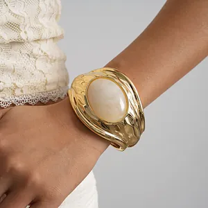 Primo piano di un bracciale a polsino in oro vintage con grande resina marmorizzata.