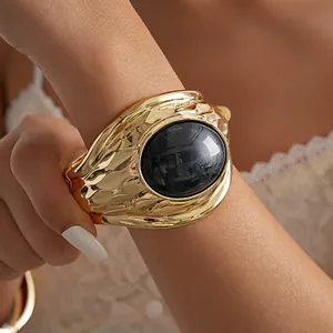 Primo piano di un bracciale rigido retrò in metallo dorato con resina nera