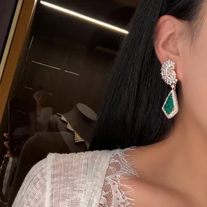 Détail de boucles d'oreilles en zircone plaqué or avec pendentif goutte vert émeraude