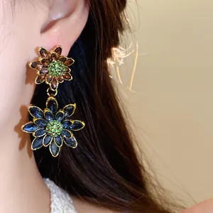 Makroaufnahme von doppelten Blumenohrringen im Palaststil mit blauen und lila Kristallen.