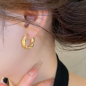 Detaillierte Nahaufnahme eleganter goldener gedrehter Creolen mit Struktur an einem Modell