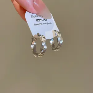Nahaufnahme der gedrehten Textur an silberfarbenen runden Metallohrringen.