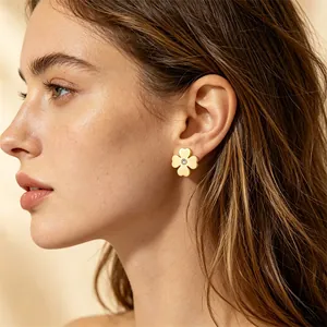 Gros plan d'un mannequin portant des boucles d'oreilles trèfle à quatre feuilles dorées