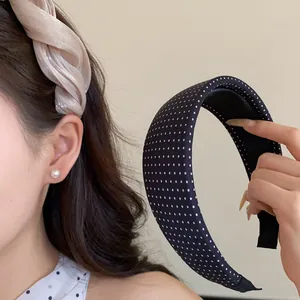 Gros plan d'un serre-tête en tissu torsadé et d'un serre-tête noir à pois blancs