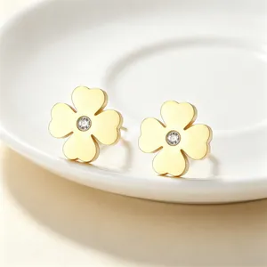 Gros plan de boucles d'oreilles trèfle en or avec cristal étincelant sur assiette.