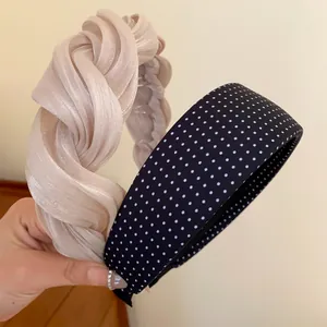 Détail d'un serre-tête plissé torsadé crème et d'un serre-tête large à pois noirs