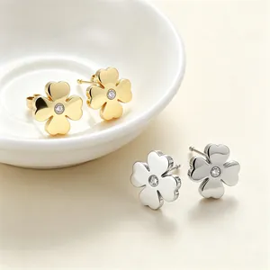 Vue détaillée de boucles d'oreilles trèfle en or et argent avec des centres en cristal.