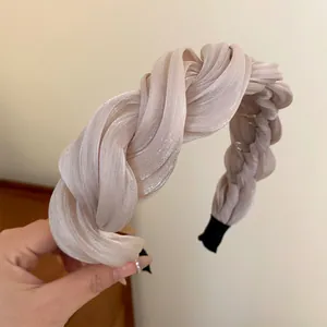 Gros plan d'un serre-tête élégant en tissu plissé torsadé couleur champagne