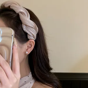 Détail rapproché d'un élégant serre-tête en tissu torsadé beige porté par un mannequin de mode