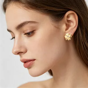 Gros plan d'un mannequin portant une boucle d'oreille trèfle en acier titane doré
