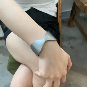 Stylish silver twisted crossover cuff bracelet worn by a model in casual setting