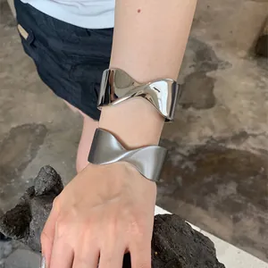 Minimalist twisted metal cuff bracelet in glossy and matte silver finishes for women.