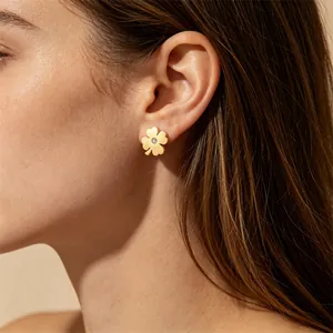 Gros plan d'une boucle d'oreille trèfle à quatre feuilles en acier titane doré avec diamant.