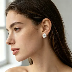 Gros plan d'un mannequin portant une boucle d'oreille trèfle argentée avec cristal.