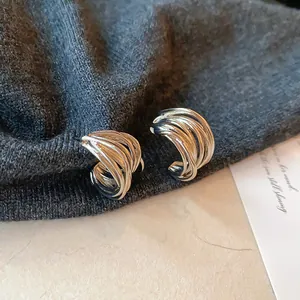 Gros plan de boucles d'oreilles torsadées argentées en forme de C sur tissu sombre
