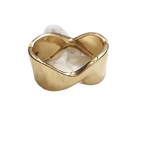 Elegant gold-toned twisted metal bangle bracelet featuring a minimalist wave design for women