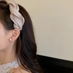 Serre-tête élégant en tissu torsadé crème sur modèle pour accessoire de cheveux chic.