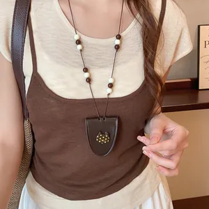 Detail van een retro lederen brillenhouder ketting gedragen op een bruine hemdje