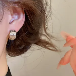 Vue détaillée d'une boucle d'oreille créole argentée torsadée en forme de C sur l'oreille