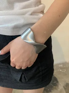 Close-up of a wide twisted silver cuff bracelet worn on a female wrist